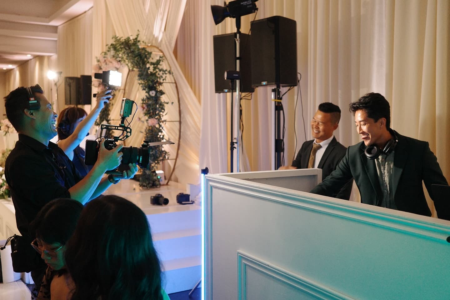The Radiate DJ and MC team behind a white wedding reception booth